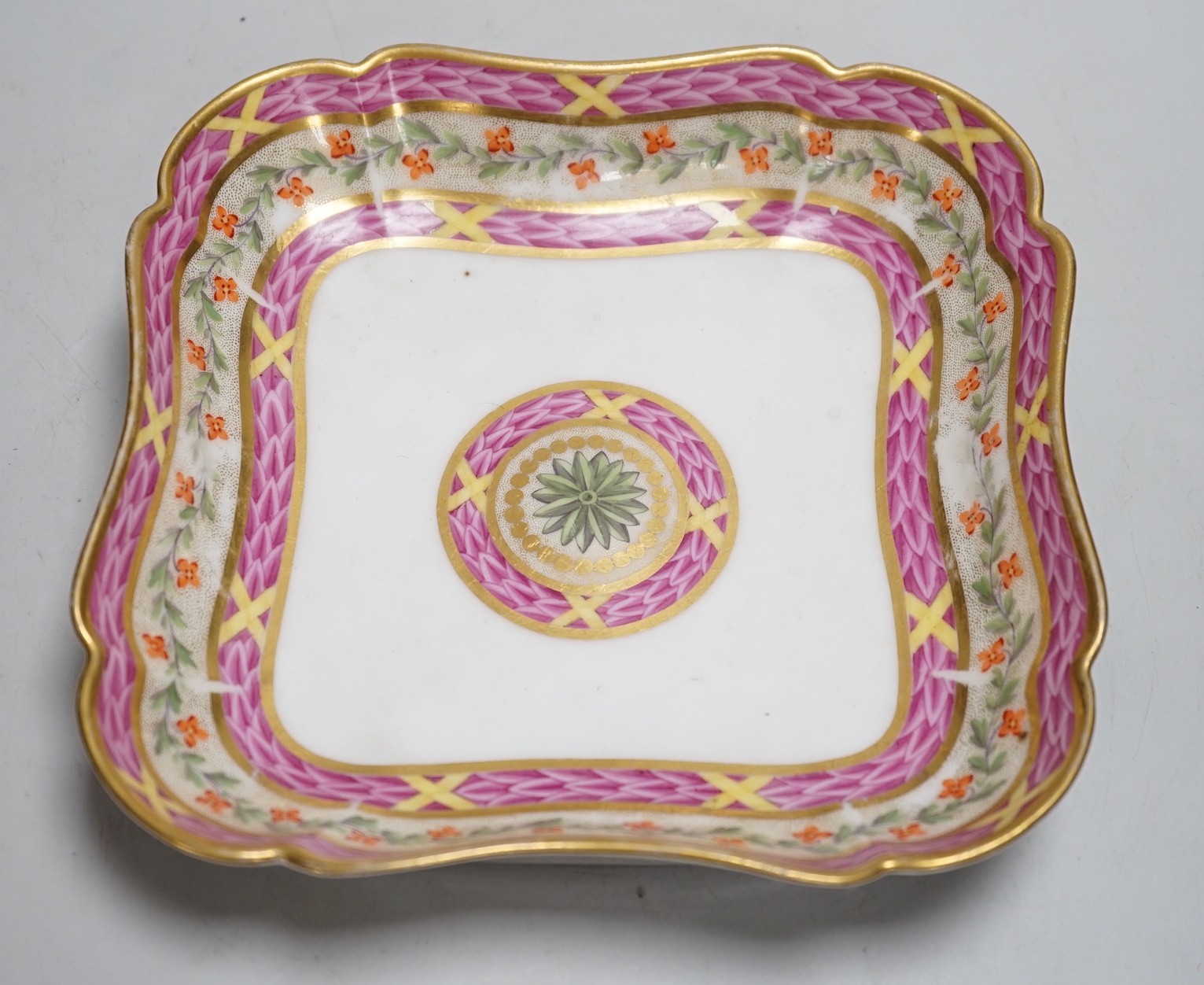 An 18th century Rue Thiroux square shaped dish painted with two bands of pink leaves, and a band of flowers above a central roundel, stencilled crown A mark in orange, the factory was also known as Porcelaines a la Reine